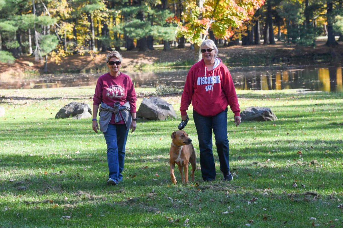 Two women walking a dog in fall at North Wood County Park near Marshfield Wisconsin