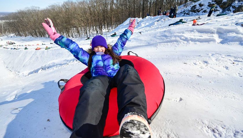 A girl ready to slide down a hill in a snow tube at Powers Bluff